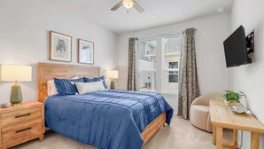 A bedroom with a bed, bedside tables, a ceiling fan, a TV mounted on the wall, and a window with curtains. - Spring Haus Near Downtown (New Braunfels)