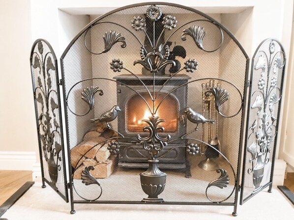 A fireplace with decorative metalwork and two birds, surrounded by a metal screen.