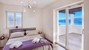 Un dormitorio con cama, mesita de noche y ventana, con vistas al exterior.