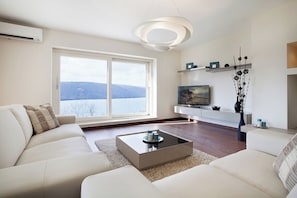 A modern living room with a sofa, coffee table, TV, and artwork. - Pool Villa Royal Blue /w Panoramic Sea View (Rasa)