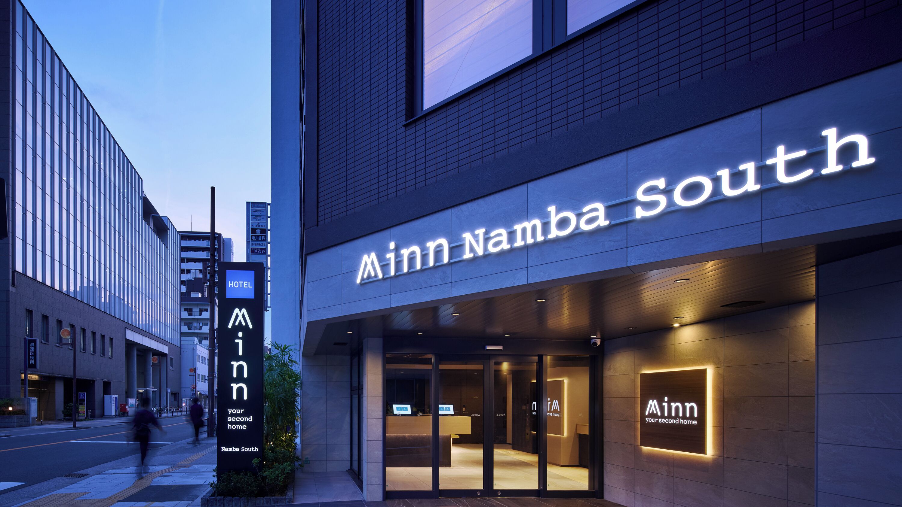 A hotel entrance with a sign reading 'Ainn Namba South' and a visible reception desk.