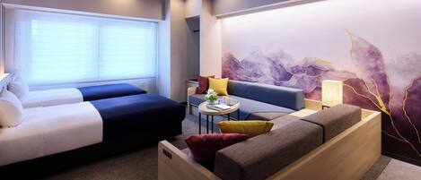 A hotel room with two beds, a sofa, a small table with a lamp, and a decorative wall.