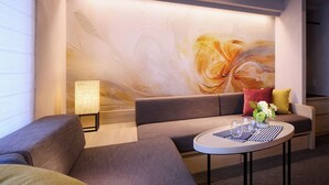 A modern hotel room with a sofa, a round table with a vase of flowers, and a large abstract painting on the wall. - Minn Namba South (Osaka)