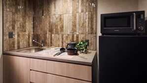 A kitchen with a marble backsplash, a black microwave, and a sink. - Minn Namba South (Osaka)