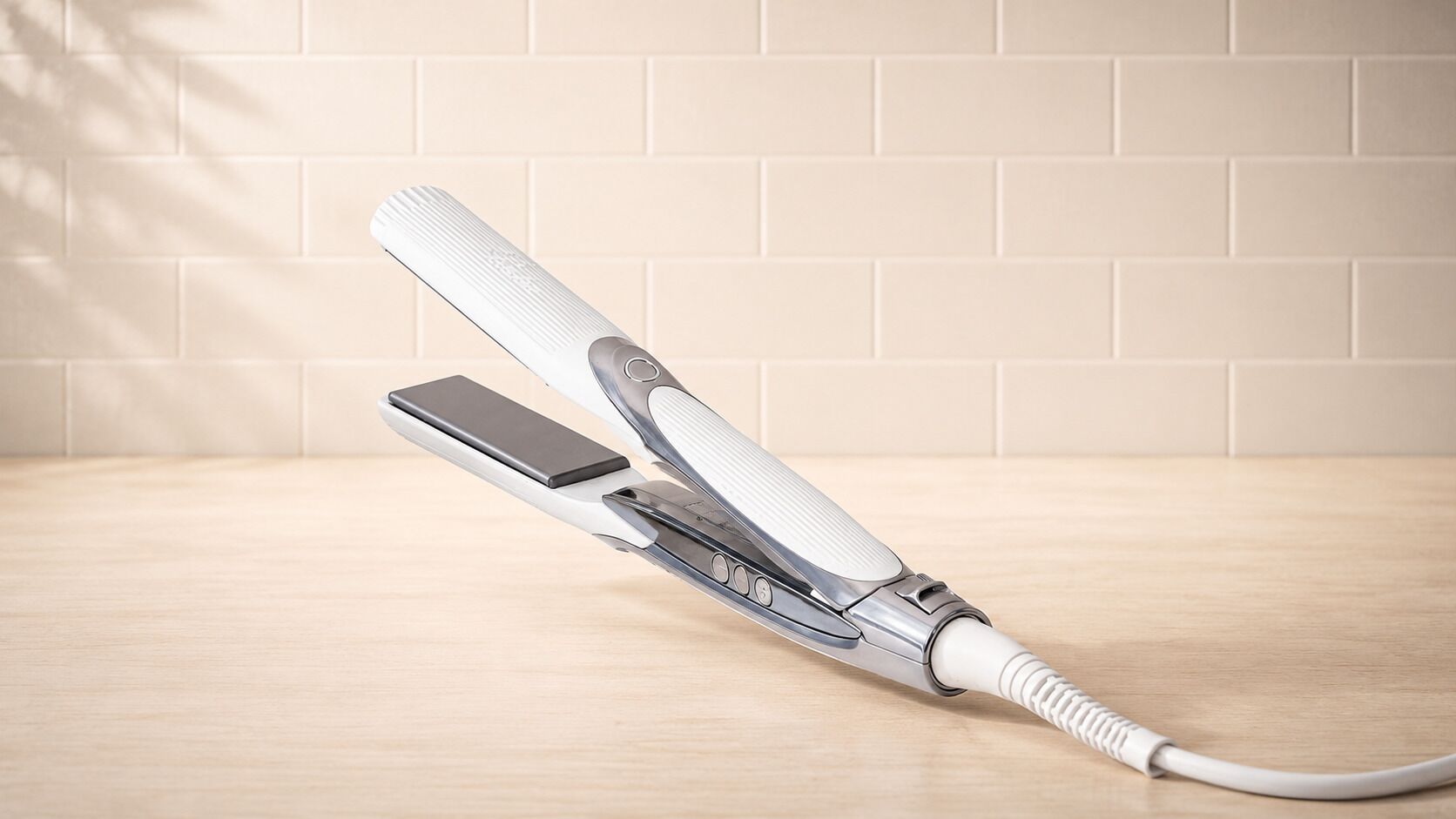 Una plancha para el cabello sobre una superficie de madera, con un muro de baldosas al fondo.
