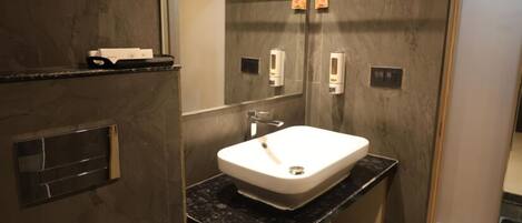 A modern bathroom with a large mirror, a white sink, and a towel rack.