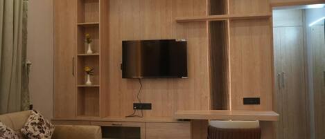 A modern living room with a flat-screen TV mounted on a wooden wall, a sofa, a coffee table, and a small side table.