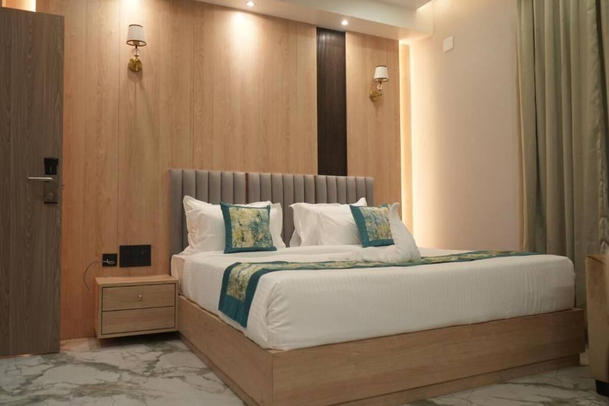 Un dormitorio con cabecera de madera, una mesita de noche y dos lámparas de pared.