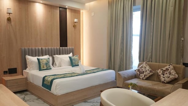 A hotel room with a bed, a sofa, a desk, and a chair. - Hotel Global Inn Keonjhar (Ghatagaon)