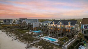 A beachfront property with multiple houses connected by walkways, a swimming pool, and a beach. - Oceanfront | Shared Pool | Beach Access | Hot Tub (North Topsail Beach)