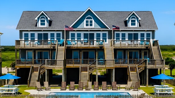 A beachfront property with a large house, a swimming pool, and a deck area. - Oceanfront | Shared Pool | Beach Access | Hot Tub (North Topsail Beach)