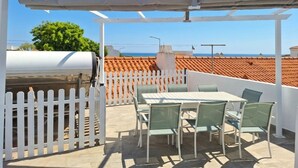 An outdoor patio with a grill, white picket fence, and a table with chairs. - 2 bedroom villa | 150m from Praia dos Pescadores | Albufeira (Albufeira)