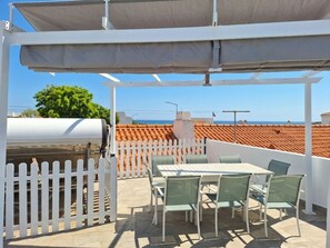 An outdoor patio with a grill, white picket fence, and a table with chairs. - 2 bedroom villa | 150m from Praia dos Pescadores | Albufeira (Albufeira)