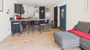 A compact living space with a kitchenette, a dining area with stools, a sofa, and a blue door. - Near the sea, apartment for 2 with terrace (Le Croisic)