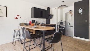 A modern kitchen with a wooden island, black chairs, and a black cabinet. - Near the sea, apartment for 2 with terrace (Le Croisic)