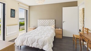 Un dormitorio con cama, mesitas de noche, escritorio y silla.