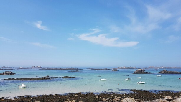 Un paisaje costero con aguas turquesas cristalinas, costa rocosa y varias embarcaciones pequeñas ancladas cerca de la orilla.