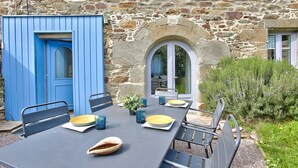 Een stenen gebouw met een blauwe deur en een tafel gedekt met borden, kommen en bekers.