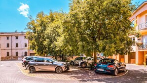 A parking area with cars, a tree, and buildings in the background. - Living 68 - a beautiful loft in Forli (Forlì)