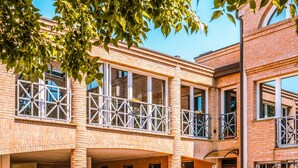 A multi-story building with a brick facade, balconies with metal railings, and large windows. - Living 68 - a beautiful loft in Forli (Forlì)