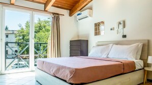 A bedroom with a bed, a nightstand, an air conditioning unit, and a view through a glass door. - Living 68 - a beautiful loft in Forli (Forlì)