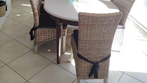 Een eethoek met rieten stoelen, een ronde tafel, een stenen muur en een hanglamp.