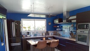 Een moderne keuken met een groot kookeiland, barkrukken, een koelkast, oven en een raam met uitzicht.