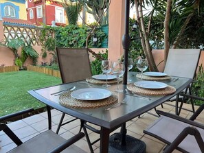 An outdoor dining area with a glass table set for two, surrounded by chairs. - Villa Juani in Playa Los Alamos (Torremolinos)