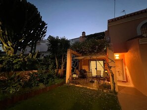 A patio area with a table and chairs, surrounded by greenery and a small pool. - Villa Juani in Playa Los Alamos (Torremolinos)
