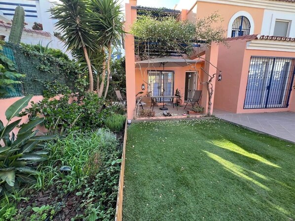 A well-maintained garden with a lawn, various plants, and a small patio area with outdoor furniture. - Villa Juani in Playa Los Alamos (Torremolinos)