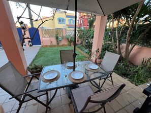 An outdoor patio with a table set for four, surrounded by chairs, and a view of a residential area with buildings and greenery. - Villa Juani in Playa Los Alamos (Torremolinos)