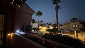A balcony with a railing, a palm tree, and a building with a dome in the background. - Villa Juani in Playa Los Alamos (Torremolinos)