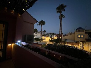 Ein Balkon mit Geländer, eine Palme und im Hintergrund ein Gebäude mit einer Kuppel.