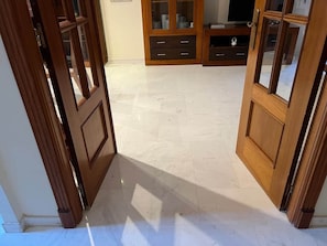 Ein Zimmer mit Holztür, Fliesenboden und einem Schrank mit Glastüren.