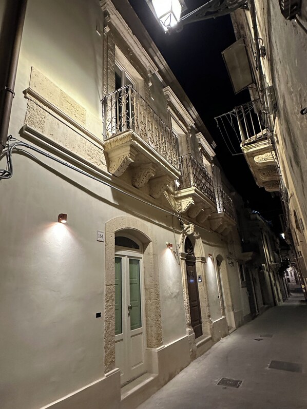 A narrow street with buildings featuring ornate balconies and arched doorways. - Romantic one-bedroom apartment in Ortigia (Siracusa)