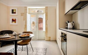 A compact kitchen with a dining area, a coffee maker, and a view through a door. - Romantic one-bedroom apartment in Ortigia (Siracusa)