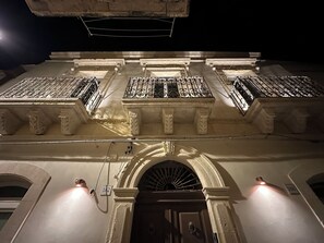 A building with a central courtyard, ornate railings, and a large arched entrance. - Romantic one-bedroom apartment in Ortigia (Siracusa)