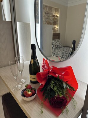 A hotel room with a bed, a mirror, a bottle of champagne, two glasses, a bowl of strawberries, and a red flower bouquet. - Romantic one-bedroom apartment in Ortigia (Siracusa)