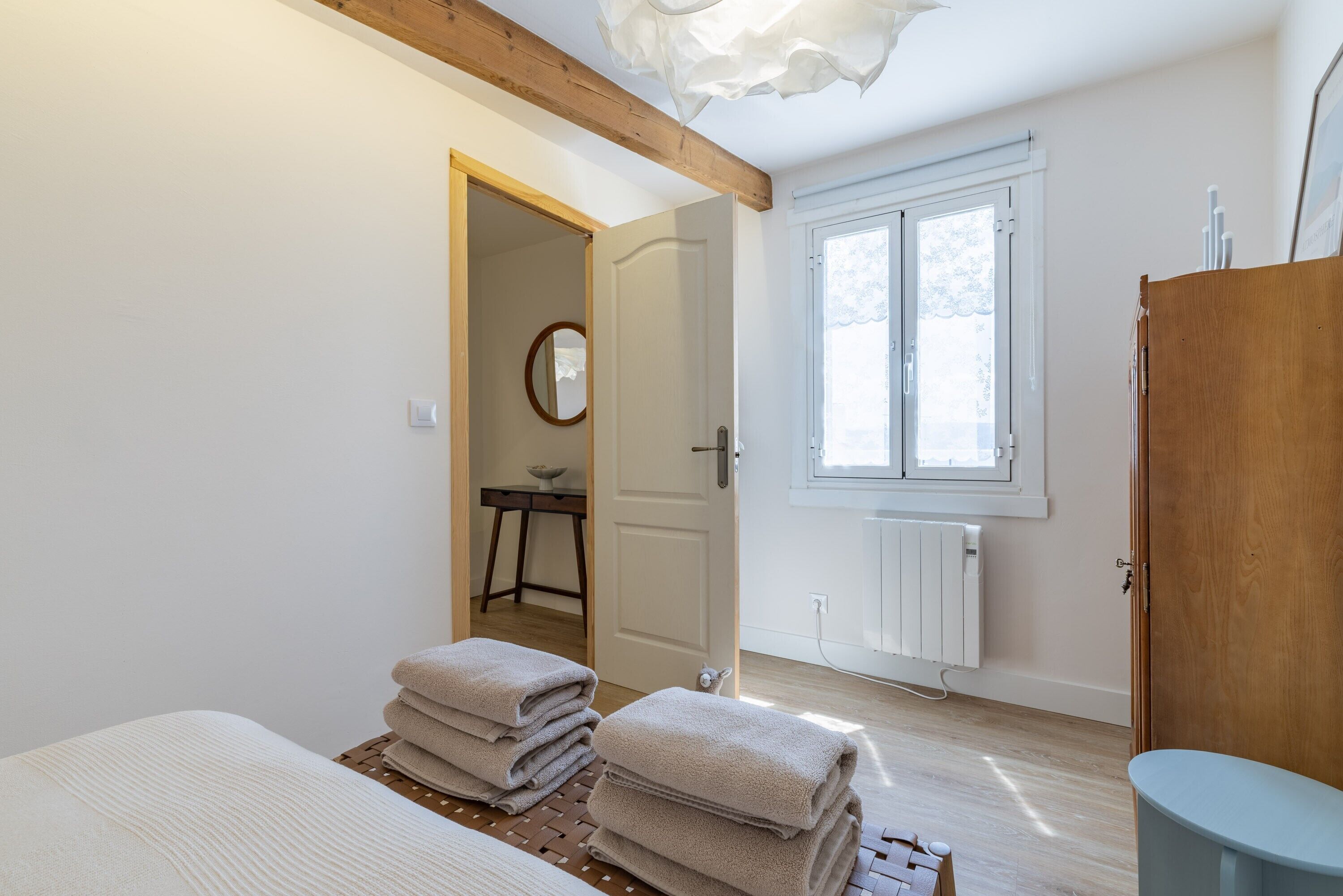 Un dormitorio con una cama, una puerta de madera, una ventana y un radiador.