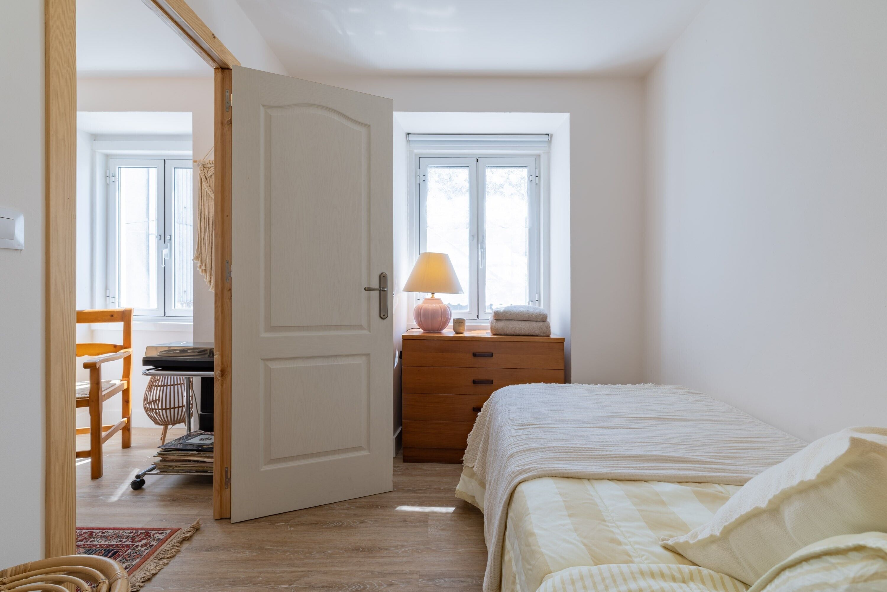 A bedroom with a bed, a dresser, a lamp, and a window.