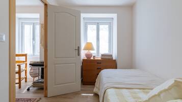 A bedroom with a bed, a dresser, a lamp, and a window.