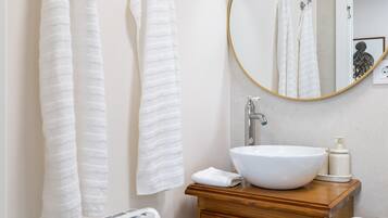 Un bagno con un mobile vanitario in legno, un lavandino bianco e due asciugamani appesi al muro.