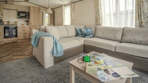 A modern living room with a sofa, coffee table, and kitchen area. - 1 bedroom accommodation in Mawgan Porth, Nr Newquay (Mawgan Porth, Nr Newquay)