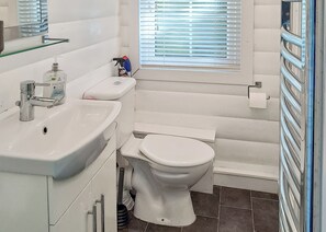 A bathroom with a white sink, toilet, and window with blinds. - 2 bedroom accommodation in Blaenau Ffestiniog (Blaenau Ffestiniog)