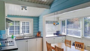 A kitchen with a dining table and chairs, a sink, and a window with blinds. - 2 bedroom accommodation in Blaenau Ffestiniog (Blaenau Ffestiniog)