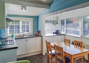 A kitchen with a dining table and chairs, a sink, and a window with blinds. - 2 bedroom accommodation in Blaenau Ffestiniog (Blaenau Ffestiniog)