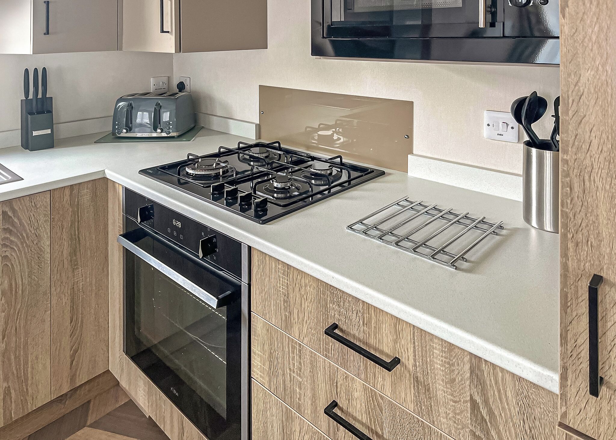 Een keuken met een gasfornuis, broodrooster, oven en houten kastjes.