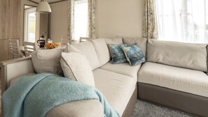 Ein modernes Wohnzimmer mit einer Couch, einem Couchtisch, einem Essbereich mit Stühlen und einer Küchenzeile.