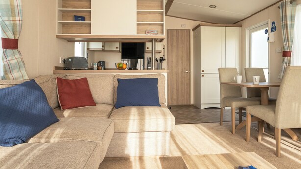 Un espace de vie chaleureux comprenant un canapé, une table à manger et un coin cuisine.