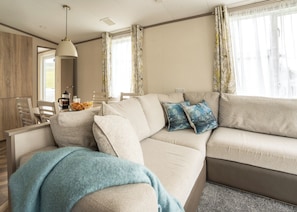 A modern living room with a sofa, a coffee table, and a dining area with chairs. - 2 bedroom accommodation in Mawgan Porth, Nr Newquay (Mawgan Porth, Nr Newquay)